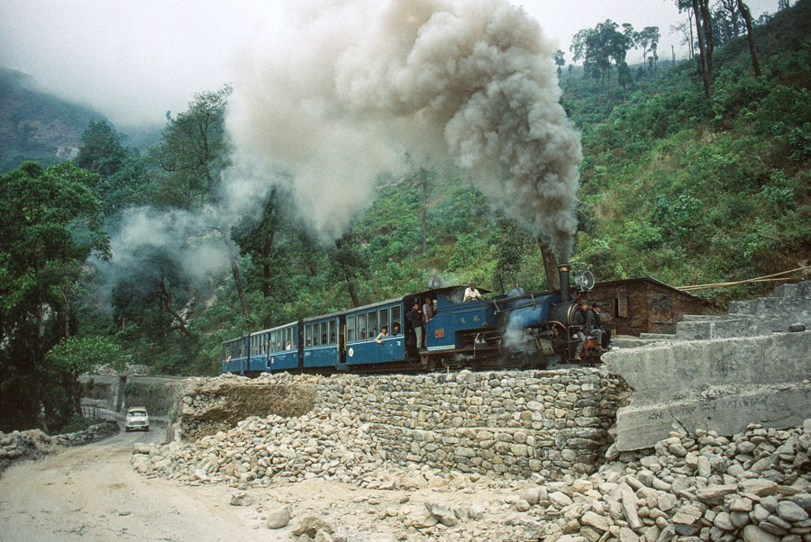 Darjeeling Himalayan Railway narrow gauge steam locomotive, class B 0-4-0ST no. 805 reverses to replace the engine on a passenger train passing a repaired landslip while heading up the mountain to Darjeeling, India,