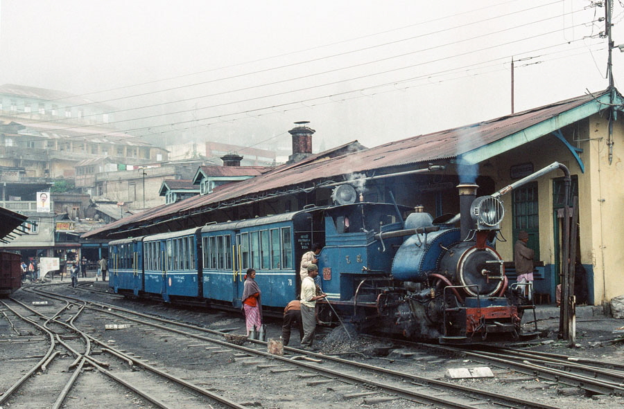 Darjeeling Himalayan Railway narrow gauge steam locomotive, class B 0-4-0ST no. 805 reverses to replace the engine on a passenger train enters Kurseong with a passenger train takes water at Kurseong station, India