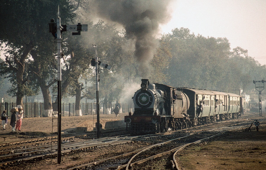 Broad gauge, oil fired, steam locomotive departs from Malakwal station with an early morning passenger train, Pakistan, 22nd December 1993.