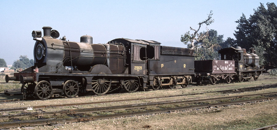 Broad gauge, oil fired steam locomotives, class SPS 4-4-0 2969 and class SGS 0-6-0 2405 stand outside the locomotive shed at Malakwal, Pakistan, 22nd December 1993