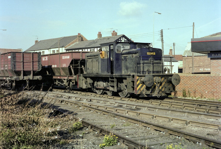 NCB Barclay 0-6-0 diesel shunting locomotive with coal train next to the crossing over North Terrace, Seaham harbour